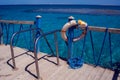 Red emergency lifebuoy hanging on fence near sea or pool