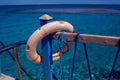 Red emergency lifebuoy hanging on fence near sea or pool