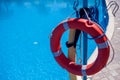 Red emergency lifebuoy hanging on fence near sea or pool