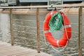 Red emergency lifebuoy with turquoise rope on pier of the city park