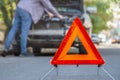 Red emergency stop triangle sign afore Destroyed car in car crash traffic accident on city road. Man driver looking on Smashed Royalty Free Stock Photo