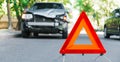 Red emergency stop triangle sign on road during a car accident. Broken gray car during road traffic accident. Car crash traffic