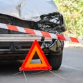 Red emergency stop triangle sign and Red warning police tape afore. Destroyed car in car crash traffic accident on city road. Royalty Free Stock Photo