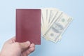 Red empty passport in the man`s hand. Dollars. Blue background