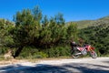 A red enduro motorcycle stands in side of the asphalt road, green nature