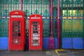 Red english phone booths with green fence Royalty Free Stock Photo