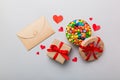 Red envelope with candy and gift box and Valentines hearts on colored background. Flat lay, top view. Romantic love Royalty Free Stock Photo