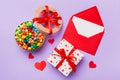 Red envelope with candy and gift box and Valentines hearts on colored background. Flat lay, top view. Romantic love Royalty Free Stock Photo