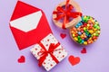 Red envelope with candy and gift box and Valentines hearts on colored background. Flat lay, top view. Romantic love Royalty Free Stock Photo
