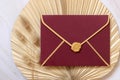 Red envelope on dry beige palm leaf near hare`s tail grass top view,  boho wedding mockup Royalty Free Stock Photo