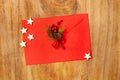 A red envelope with fir branch, hollies and white stars on a wooden background