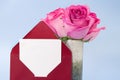 Red envelope with place of paper for text and vase of pink roses on blue background Royalty Free Stock Photo