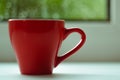 The red espresso cup on white windowsill. On background window and rain. Royalty Free Stock Photo