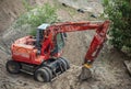 Red excavator digging a pit