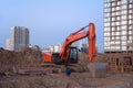 Red excavator during earthworks at construction site. Backhoe digging the ground for the foundation and for laying sewer pipes Royalty Free Stock Photo