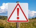Red Exclamation Mark in Triangle Warning Sign on Wooden Post under Blue Sky Royalty Free Stock Photo