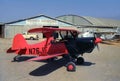 Experimental single engine red black biplane outside a hanger. 