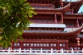 Red exterior of tall traditional Chinese architecture facade and trees temple