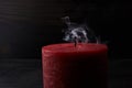 Red extinguished candle with smoke trailing off the wick on black background Royalty Free Stock Photo