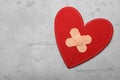 Red fabric heart with sticking plasters on light grey stone table, top view. Space for text Royalty Free Stock Photo
