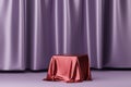 Red fabric placed on podium or pedestal for products or advertising near to purple curtains.