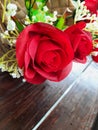 Red fabric roses in basket on brown wooden table