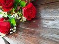 Red fabric roses on brown wooden table