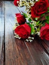 Red fabric roses on brown wooden table