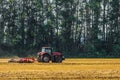 Red farming tractor is working in the field. Disc harrow for crushing stubbles. Royalty Free Stock Photo