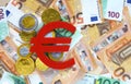 Red felt Euro currency symbol and golg chocolate euro cents on euro banknotes background.