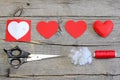 Red felt heart, cut felt parts in shape of a heart, paper pattern, scissors, thread, needle on a wooden table. Felt heart craft Royalty Free Stock Photo