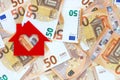 Red felt small house on fifty euro banknotes background. Real estate loan concept.