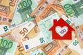Red felt small house on right side of euro banknotes background. Money for a dream house.