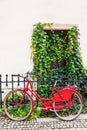 Red female bicycle leaning against a rail fence