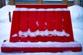 A red fence in snow on a street in winter