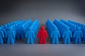 Red figure among blue figures, standing out against gray background, individuality highlighted Royalty Free Stock Photo