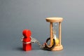 The red figure of a man is handcuffed to an hourglass. Dependence, there is little time left. Streamline business, increase Royalty Free Stock Photo