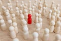 Red figure stands out of crowd with white figurines on table