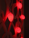 Red fir cones Christmas lights garland on dark background. Christmas or new year led lights garland. Blurred glowing light bulb Royalty Free Stock Photo