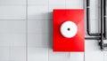 Red fire alarm box with white button mounted on white tiled wall with pipes image Royalty Free Stock Photo