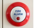 Red fire alarm button on a light wooden wall panel isolated on white background Royalty Free Stock Photo