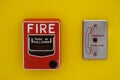 Red Fire alarm pull station Switch install on bright yellow wall Royalty Free Stock Photo