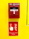 Red fire alarm switch on a vibrant yellow wall with instructions Royalty Free Stock Photo