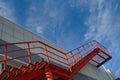 Red fire escape on the facade of the building against a bright blue sky Royalty Free Stock Photo