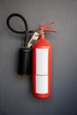 Red fire extinguisher hanging against grey wall background Royalty Free Stock Photo