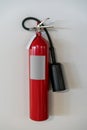 Red fire extinguisher hanging against white background Royalty Free Stock Photo