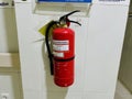 A red fire extinguisher is mounted on a white tiled wall. Royalty Free Stock Photo
