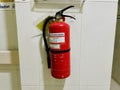 A red fire extinguisher is mounted on a white tiled wall. Royalty Free Stock Photo