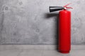 Red fire extinguisher near grey wall, space for text Royalty Free Stock Photo