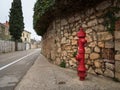 Red fire hydrant in front of a stone wall